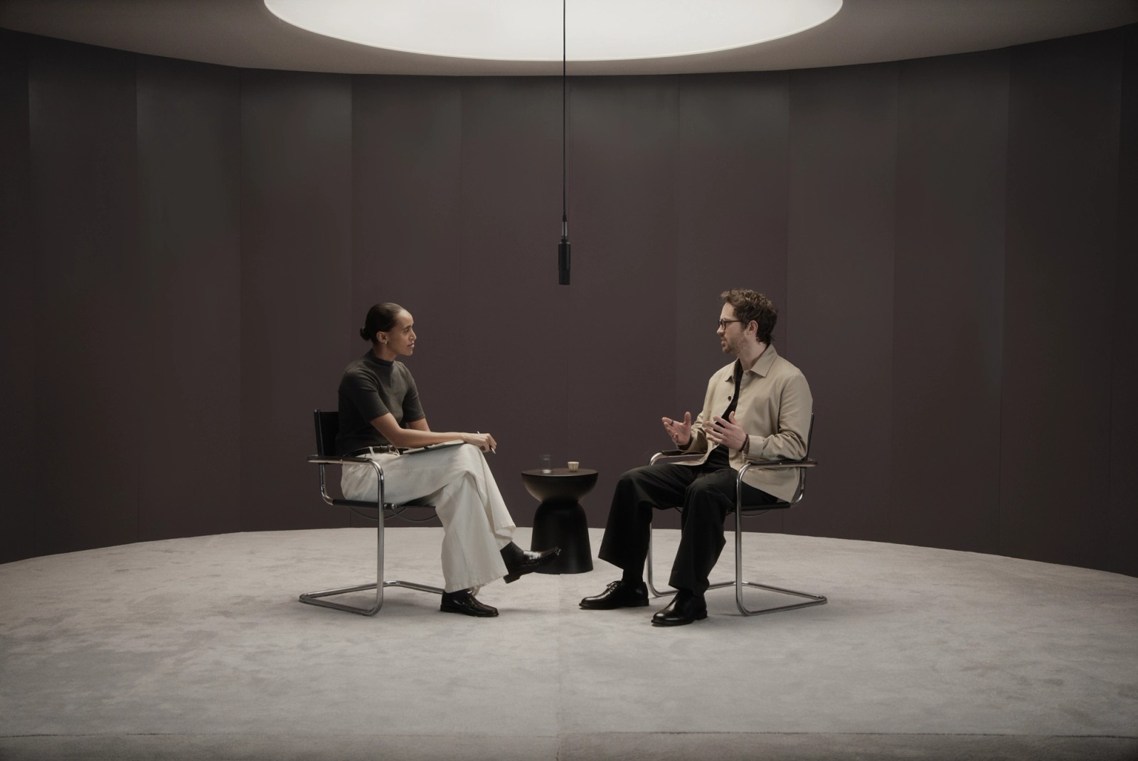 Two people speaking in a minimal studio setting